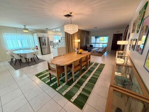 A modern kitchen with a dining area, a chandelier, and a living room with a sofa and a coffee table. - Luxury Hollywood Lakes Villa (Hollywood)