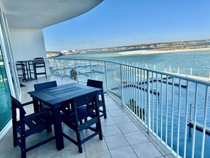 Un balcón con mesa y sillas, con vista a la costa y una playa lejana.