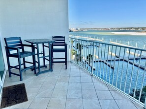Un balcón con mesa y sillas, vista al mar y barandilla blanca.