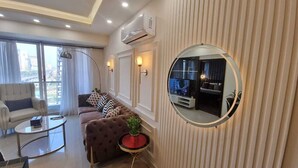 Un salon moderne avec un canapé, un fauteuil, une table basse et un miroir rond.