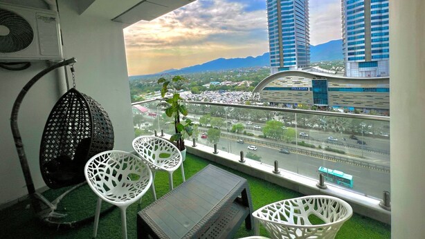 Un balcon offrant une vue sur le paysage urbain, avec notamment un pont et des immeubles de grande hauteur.