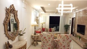 Un salon avec un canapé, une table basse, un téléviseur et un grand miroir.