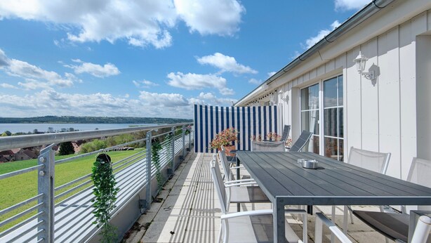 A balcony with a table and chairs, a railing, and a view of the landscape. - Family Apartment with Lake View (Spalt)