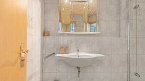A bathroom with a sink, mirror, and shower. - Family Apartment with Lake View (Spalt)