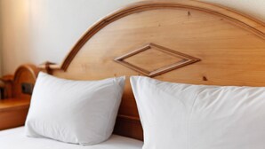 A bed with white bedding and two pillows, a wooden headboard with a geometric design, and a wooden nightstand with a lamp. - Family Apartment with Lake View (Spalt)