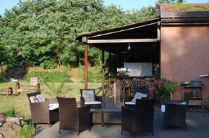 Eine Terrasse im Freien mit Korbmöbeln und Grillplatz.