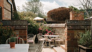 An outdoor patio with a table and chairs, surrounded by brick walls and potted plants. - The Great Decoy (Hurstbourne Tarrant)