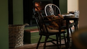 A room with a fireplace, a framed artwork, a chair, and a table. - The Great Decoy (Hurstbourne Tarrant)