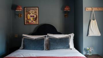 Una camera da letto con un letto, due lampade a parete, un quadro e una borsa appesa.
