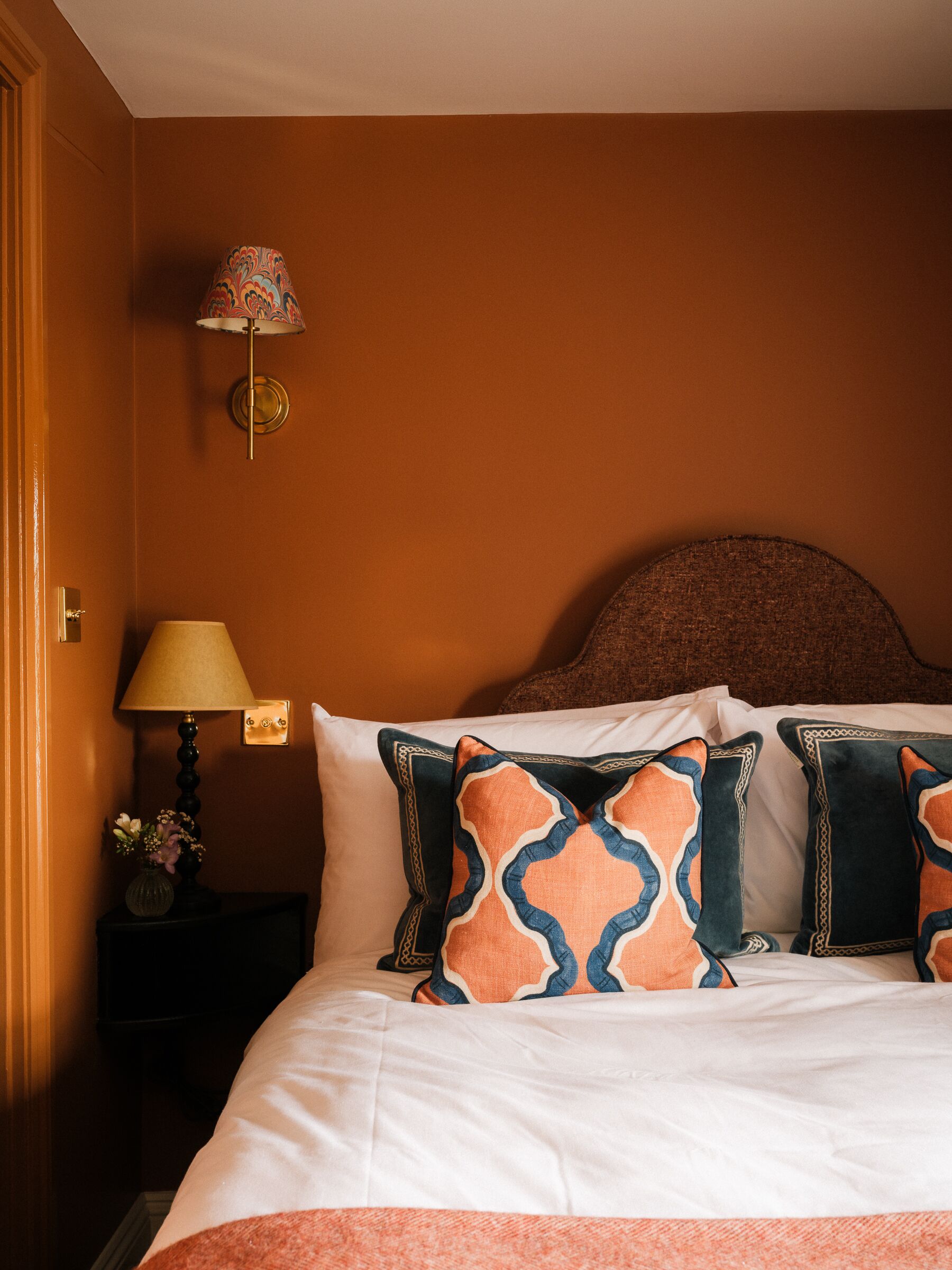 Ein Hotelzimmer mit Bett, Nachttisch mit Lampe und Wandleuchte.