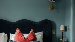 A neatly made bed with patterned pillows, a dark headboard, and a bedside table with a lamp and a small vase. - The Great Decoy (Hurstbourne Tarrant)