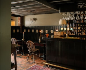 A bar area with wooden furniture, a tiled floor, and a wall-mounted light fixture.