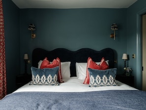 A bedroom with a dark headboard, two bedside tables with lamps, and patterned pillows. - The Great Decoy (Hurstbourne Tarrant)