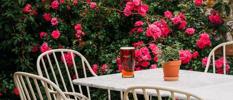 A table with chairs, a glass of beer, and a potted plant.