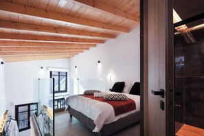 A bedroom with a large bed, wooden ceiling beams, a glass wall, and a view of the outside. - My Luxury Prime Suite (Rethymno)