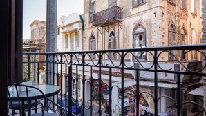 A balcony with a wrought iron railing, a round table, and chairs.