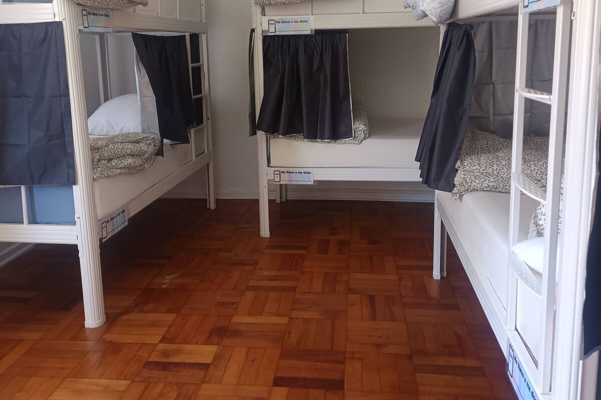 Ein Zimmer mit drei Etagenbetten, Holzboden und einer weißen Wand.