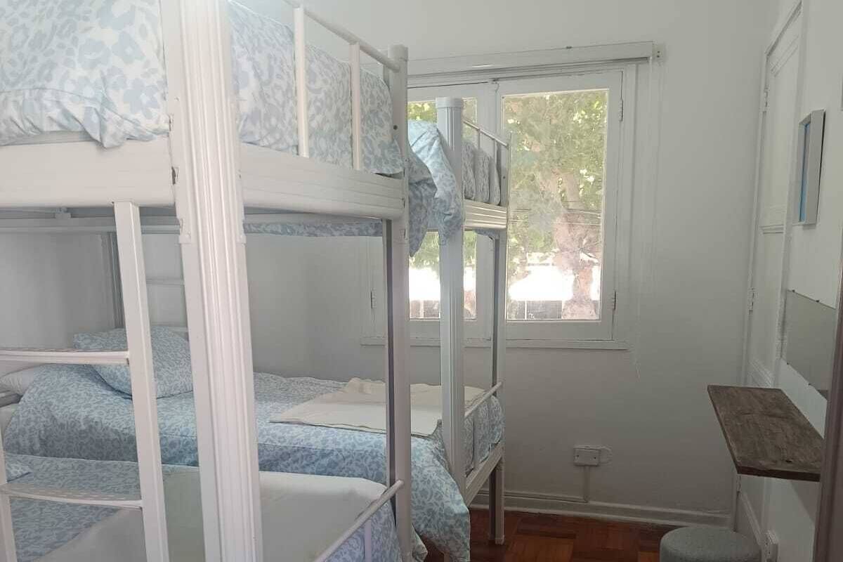 Ein Schlafsaalzimmer mit Etagenbetten, einem kleinen Schreibtisch und einem Fenster.