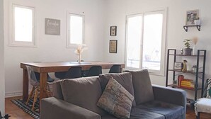 A living room with a sofa, a dining table, and a bookshelf.