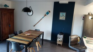 Ein Essbereich mit Holztisch, Stühlen, einer Hängelampe, einem hölzernen Baseballschläger, einem gerahmten Bild und einem Kühlschrank.