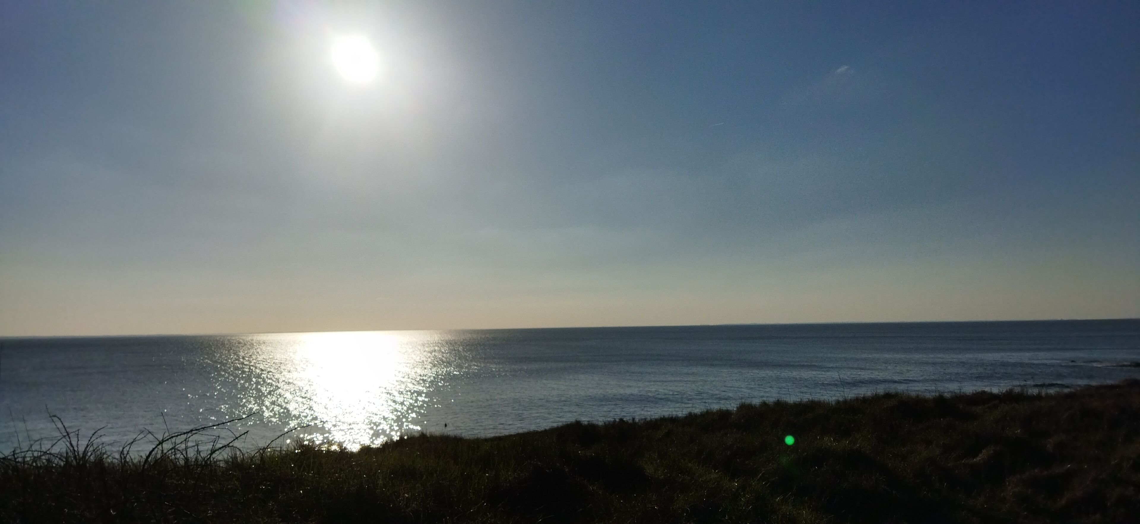 Ein Strand, auf dem sich die Sonne im Wasser spiegelt.