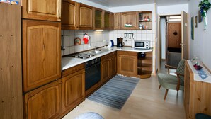 Une cuisine dotée de meubles en bois, d’un four à micro-ondes, d’une machine à café et d’un coin repas avec une chaise et une table.