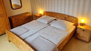 A wooden bed with two nightstands, a mirror, and striped wallpaper. - Apartment 'Fewo Mirja' with Shared Terrace, Shared Garden and Wi-Fi (Pellworm)