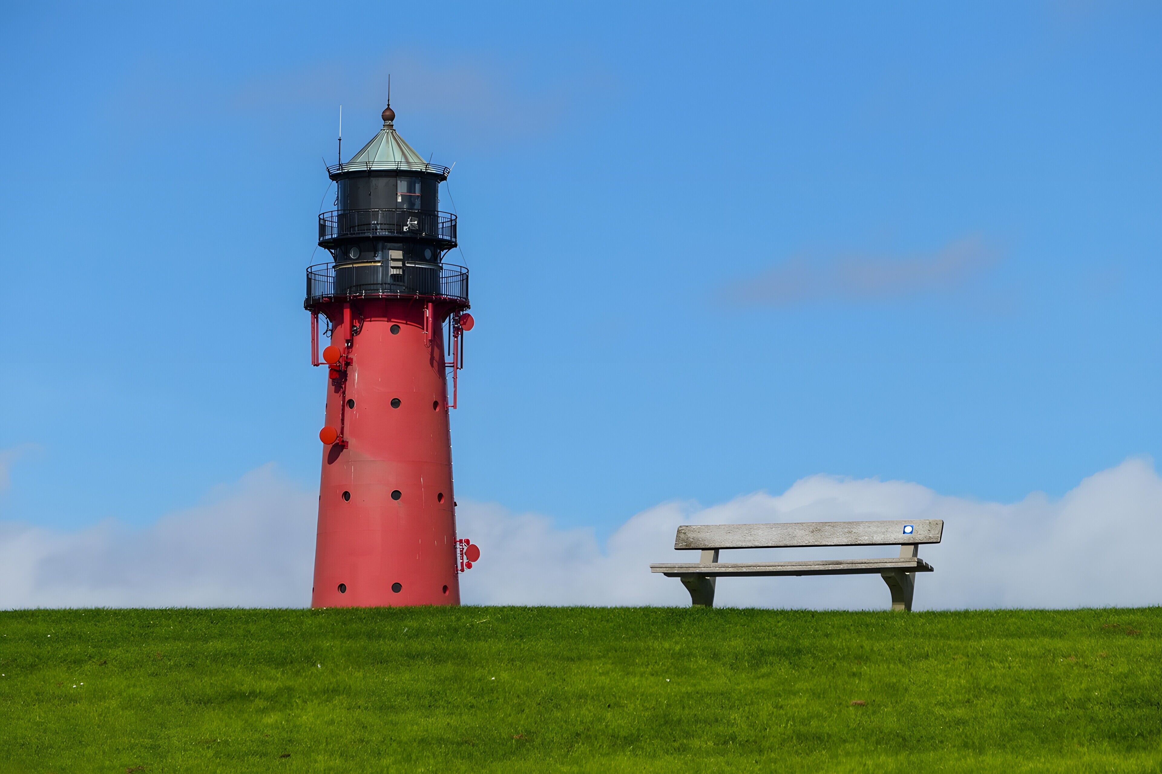 Ein roter Leuchtturm mit einer Bank in der Nähe.