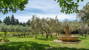 An outdoor garden with a central fountain, surrounded by trees and greenery. - Gite le Bananier – 6 guests (Jonquières)