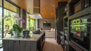 Cozinha moderna com uma ilha grande, eletrodomésticos embutidos e vista para um jardim exuberante.