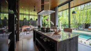 Uma cozinha moderna com ilha central, grandes janelas e vista para uma piscina.