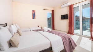 Ein Schlafzimmer mit einem Bett, einem Flachbildfernseher, einem Fenster mit Vorhängen und einem Bild an der Wand.