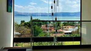 A room with a large window offering a view of a lake and distant mountains. - Casa Cuba - Spectacular Lake and Mountain View (Jocotepec)
