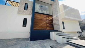 A modern building with a large wooden door, white walls, and a stone facade. - Casa Cuba - Spectacular Lake and Mountain View (Jocotepec)
