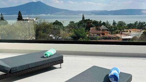 A rooftop terrace with two lounge chairs, one with a green towel and the other with a blue towel. The terrace overlooks a body of water and distant mountains. - Casa Cuba - Spectacular Lake and Mountain View (Jocotepec)