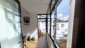 Ein Flur mit Holzboden, einer Tür mit Milchglasfenstern und Blick ins Freie durch große Fenster.