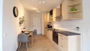 Una cocina moderna con armarios de madera, horno empotrado y comedor con mesa y sillas.