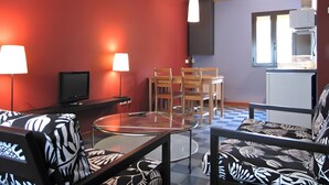A room with a red wall, a wooden ceiling, a glass table, and a kitchen area with a refrigerator. - Country House 'Villabamba 4' with Mountain View, Shared Terrace and Wi-Fi (Valdeavellano de Tera)