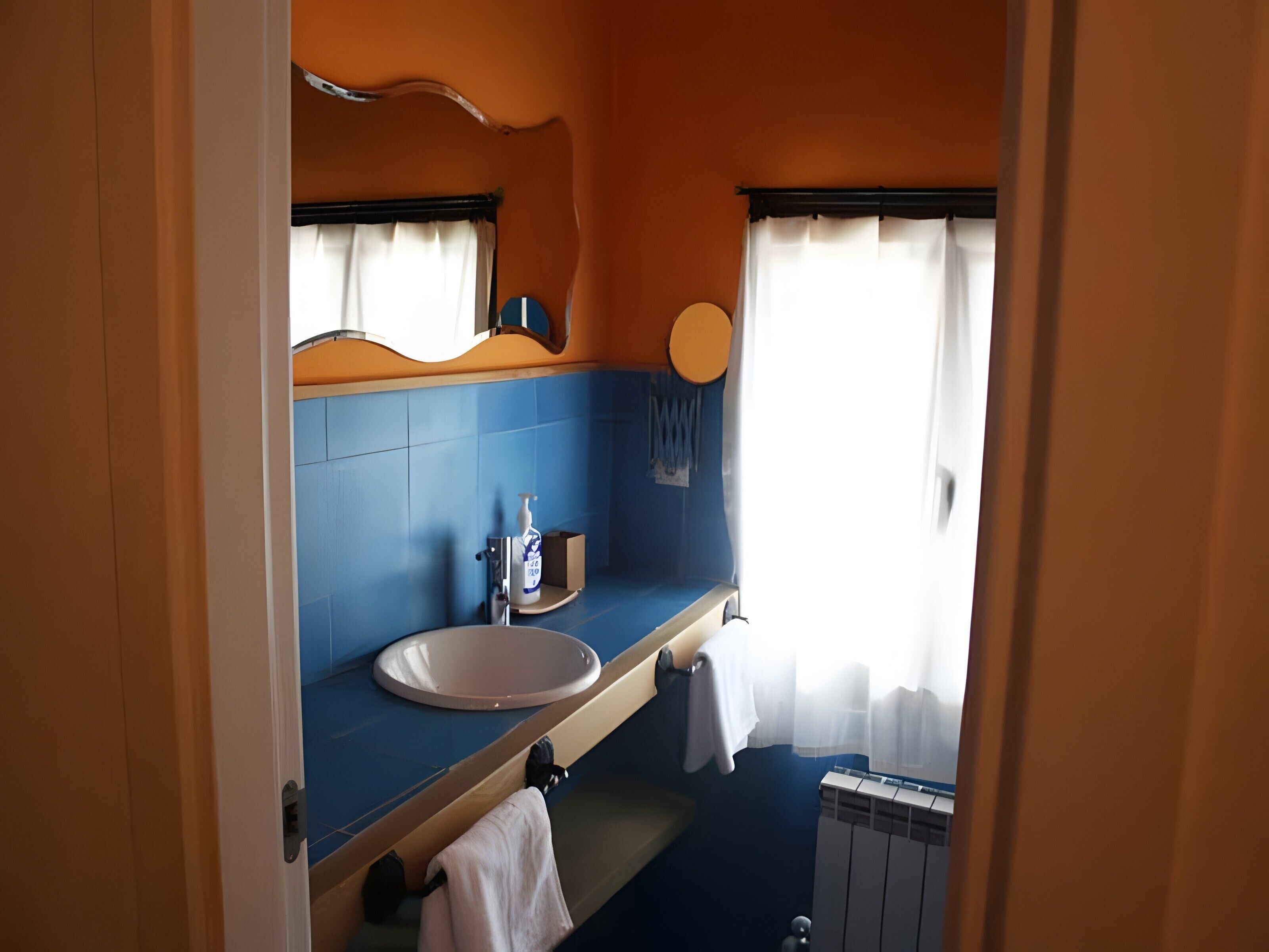 Une salle de bain équipée d’un lavabo, d’un miroir, d’un porte-serviettes et d’un radiateur.