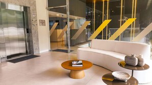 A modern lobby with a white sofa, a coffee table, and a reception desk. - Falésia Alliance (João Pessoa)
