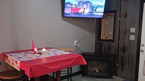 A cozy room with a wooden ceiling, a television mounted on the wall, a dining table with a red tablecloth, and a patterned rug on the floor. - Loft suite with cozy Queen minutes from Makers Mark , Log Still , Gethsamane (Loretto)