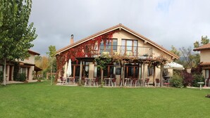 Un bâtiment à deux étages doté d’un patio couvert, d’un espace extérieur aménagé pour s’asseoir et d’une pelouse bien entretenue.