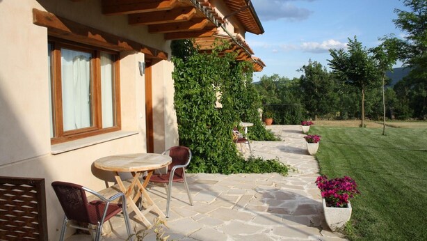 Une terrasse avec un sol en pierre, une pergola en bois et des sièges d’extérieur.