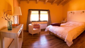 Une chambre à coucher avec un lit, une chaise, un bureau, une lampe et une fenêtre avec des rideaux.