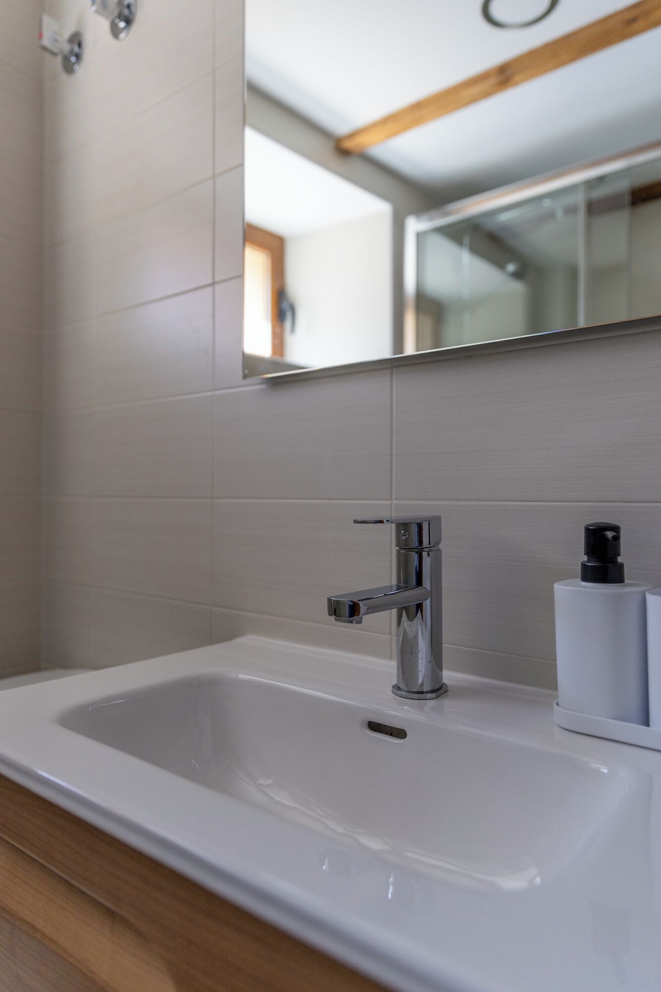 A bathroom with a white sink, chrome faucet, and a mirror above it.