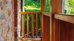 A wooden balcony with a stone wall and a view of a green landscape. - La Casita de Verdiago (Cremenes)