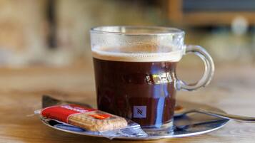 A clear glass mug with a handle, filled with a dark liquid, possibly coffee, on a wooden table.