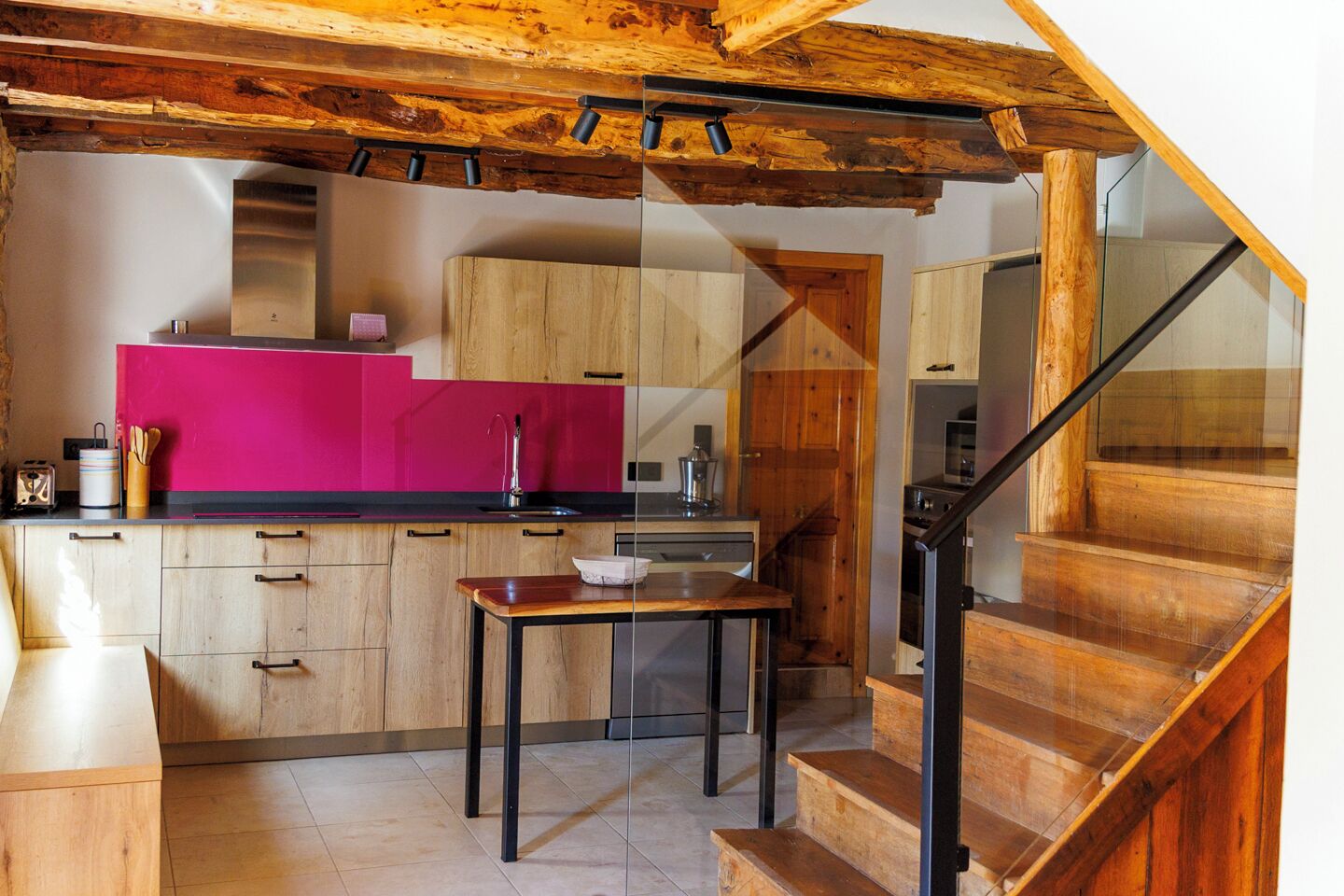 Una cocina moderna con armarios de madera, encimera rosa y una escalera de madera.