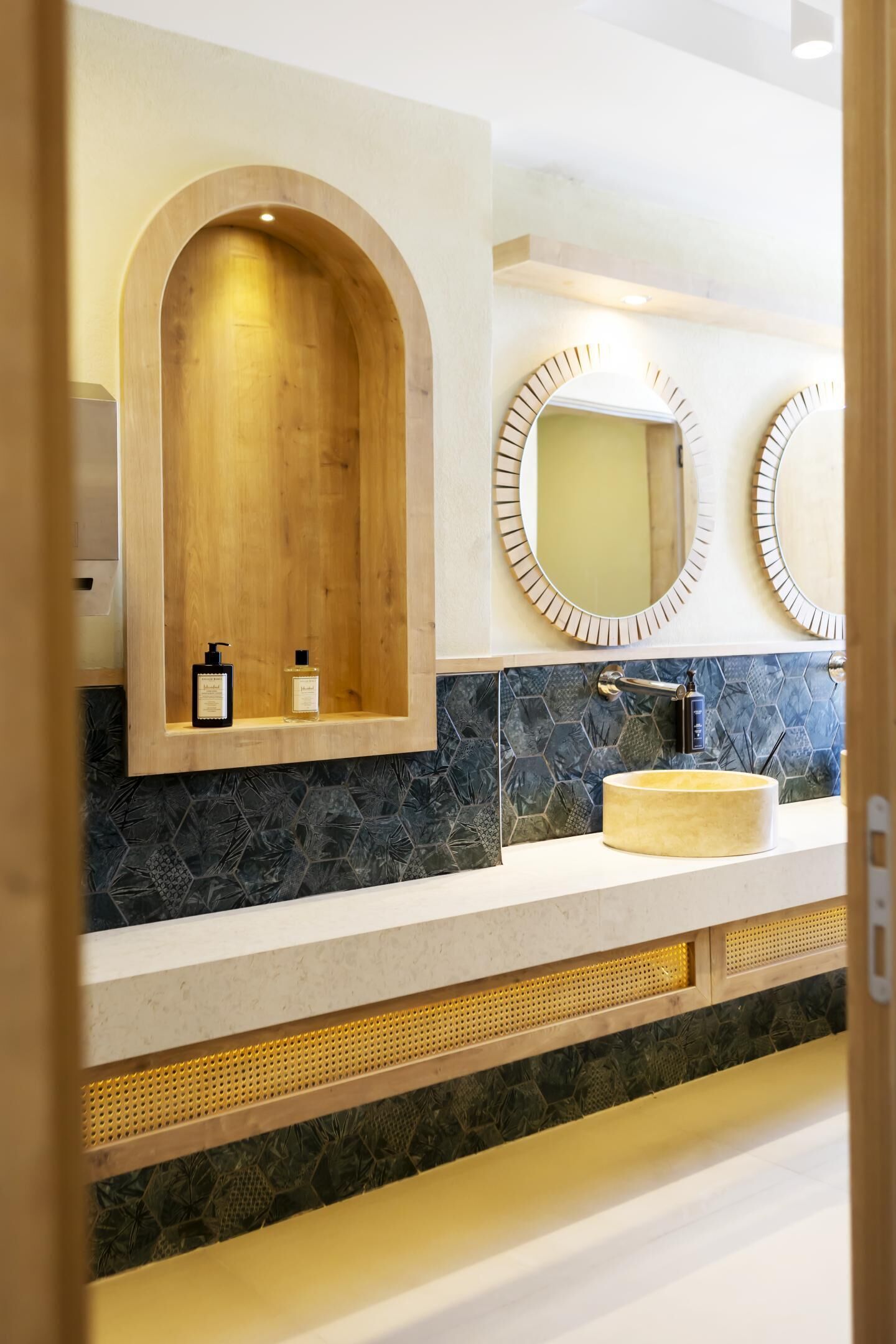 A bathroom with a wooden vanity, a sink, and two wall-mounted mirrors.