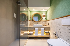 A modern bathroom with a glass shower enclosure, a sink with a mirror, and a toilet. - BaÅŸka Resort Bodrum - All inclusive (Bodrum)